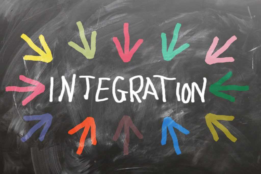 Integration concept with colorful arrows pointing toward the word integration on a chalkboard.